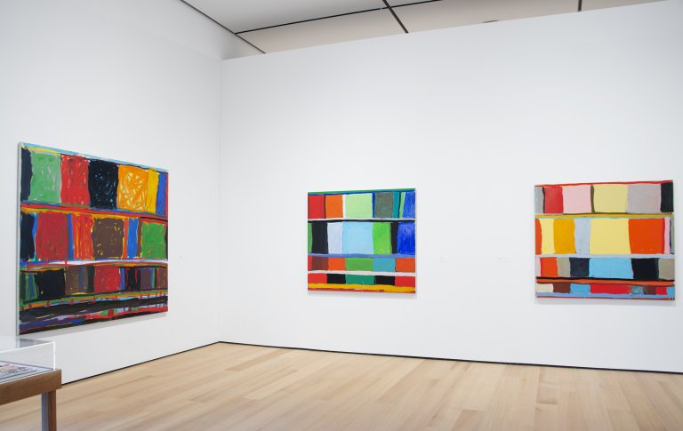 Abstract paintings by Stanley Whitney featuring a structured grid of colorful rectangular blocks, separated by thin lines, creating a rhythmic composition shown here in an exhibition at Buffalo AKG Art Museum