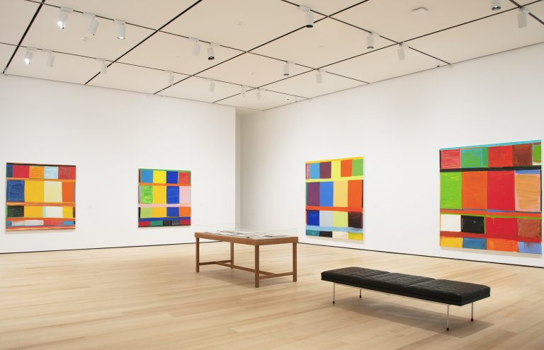 Abstract paintings by Stanley Whitney featuring a structured grid of colorful rectangular blocks, separated by thin lines, creating a rhythmic composition shown here in an exhibition at Buffalo AKG Art Museum
